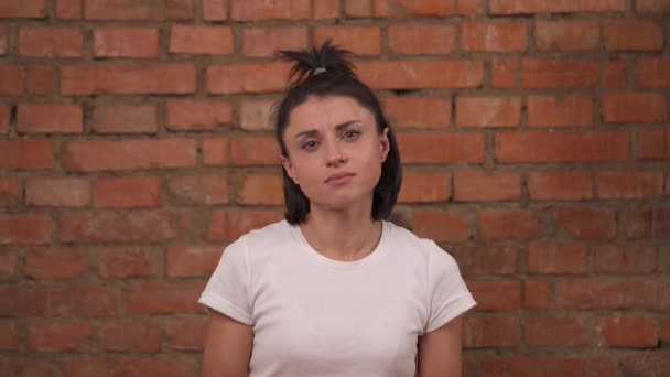 Närbild Osäker Flicka Vit Shirt Stående Isolerad Mot Tegelvägg Bakgrund — Stockvideo