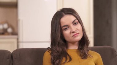 A closeup of pretty brunette's face looking bored and unhappy; the camera moves to the left and a bearded man's face in glasses looking down