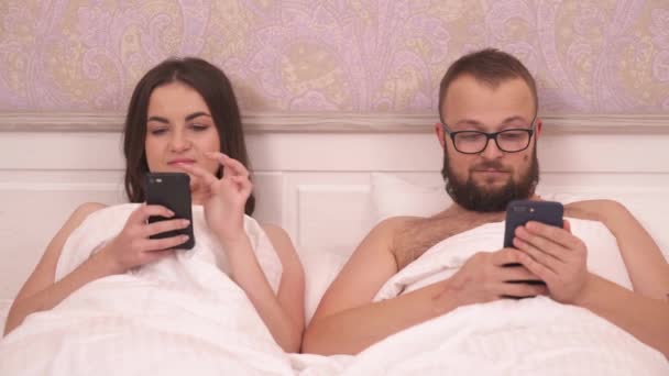 Young Brunette Bearded Man Glasses Lying Bed Holding Phones Scrolling — 图库视频影像