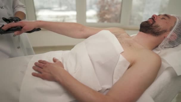 Ein Mann Liegt Auf Der Couch Einem Schönheitssalon Weibliche Hände — Stockvideo