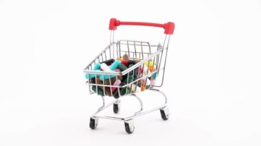 Shopping cart filled with medical pill capsules is rotating on the turntable. Isolated on the white background. Close-up.