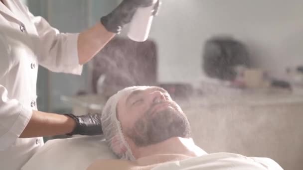 Woman Beautician Black Gloves Holding Bottle Sprinkling Spray Man Face — Stockvideo