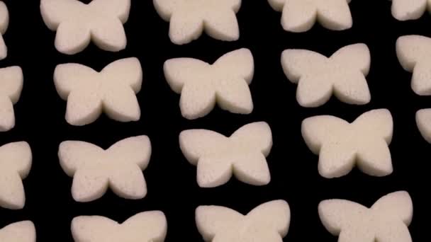 Small Butterfly Shaped White Candies Rotating Isolated Black Background — Vídeos de Stock