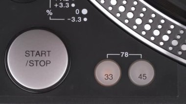 Close-up of a man finger pressing a start button on the LP vinyl record player.