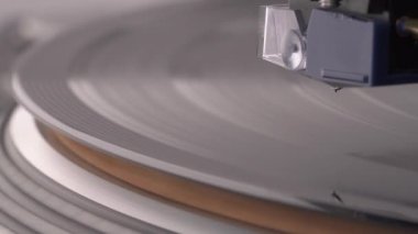 Macro shooting of coil cartridge lifting to vinyl record rotating on the turntable.