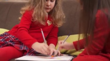 Charming little girls are drawing with colored pencils