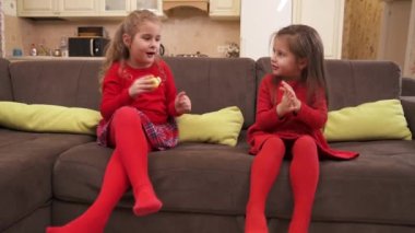 Adorable little girls play together at home, clap their hands and have fun