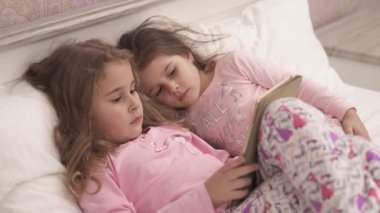 Two little girls using tablet pc in bed before sleeping