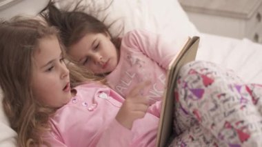Close up view of two little girls using tablet pc in bed before sleeping