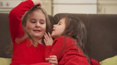 Cute children sharing secrets. Little girl whispering something in a friends ear.
