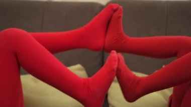 Two little girls in red tights playing in bed, pushing each others legs