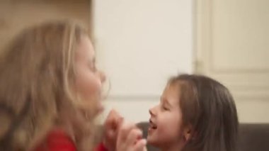 Close-up view of a cute kids holding each others hands, jumping and falling on a sofa