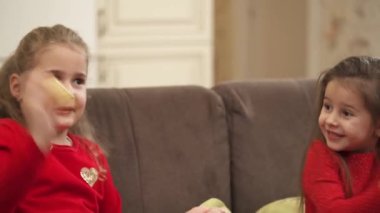 Adorable preschool girls laughing, clapping hands and having fun together at home