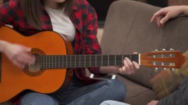 Young beautiful girl plays an acoustic guitar and kiss her boyfriend after that