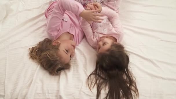 Små Flickor Rosa Pyjamas Som Ligger Sängen Upp Och Ner — Stockvideo