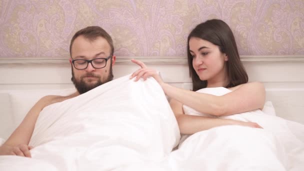 침대에 사랑하는 커플의 소녀가 담요를 올리고 그녀가 불쾌하게 도놀랐다 인간은 — 비디오