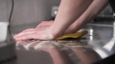 Mans hands kneading a piece of dough on the table in the professional kitchen. Fresh noodles preparation in a restaurant