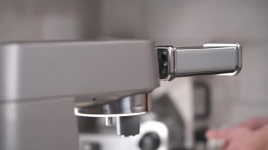 A close-up of noodle cutting machine working and a hand putting a piece of dough into it and catching the strands of noodles. Fresh noodles preparation in a restaurant