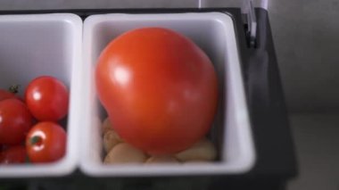 White plastic containers with tomatoes, garlic, cherry tomatoes, butter, pepper and oil in the professional kitchen