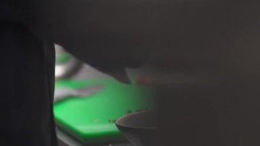 A close-up side view of hands in black gloves grating cheese into the bowl standing on the kitchen table