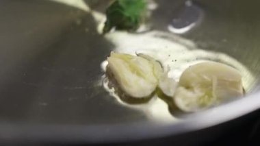 A close-up view of garlic and spinach with oil sizzling in the frying pan