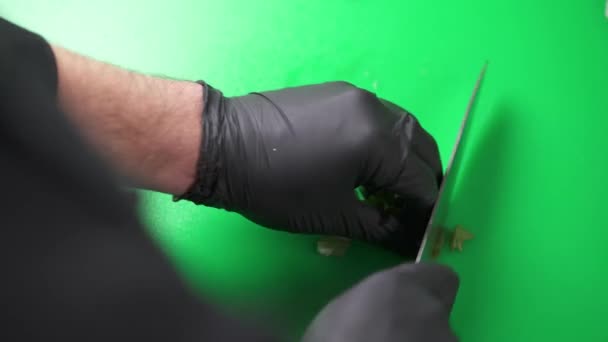 男子双手戴黑色手套在绿板上切香草的头像 — 图库视频影像