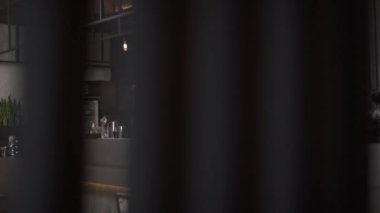 A barman is putting ice into a glass jug and mixing it with a spoon. A bartender is at work at the bar counter