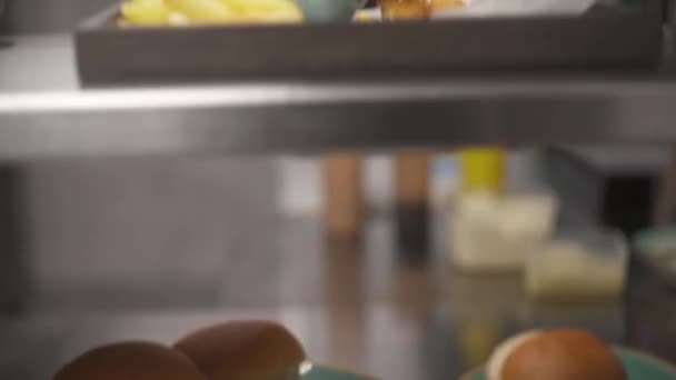 上面有盘子和面包的贝壳 相机从底部向上移动 停在上层架子上 还有一个托盘 上面放着一个汉堡包 法式薯条和一个加红酱油的茶壶 — 图库视频影像