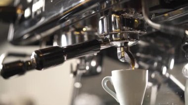 A close-up of a coffee machine with a cup and coffee pouring into it. Coffee making in a bar