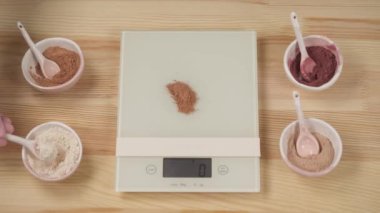 Top view of how a girl weighs organic herbal powders to make a natural facial scrub.