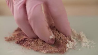 Close-up of a girl mixing powders from different herbs with her hand. Process of making natural facial scrub.