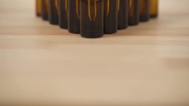 Close-up dolly shot past arranged in triangle amber small bottles with white caps on the wooden background.