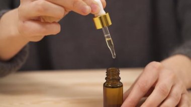 Şişenin içine dökülen sıvı ve damlacıklarla bir pipeti sıkan kadının yakın çekim görüntüsü..