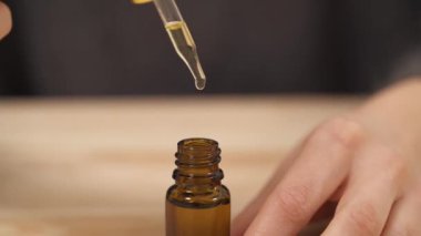 Kadının elinin bir pipetin suyunu sıkarken ve hızla doldururken yakın plan görüntüsü. Şişenin üstündeki pipeti tutarken damlacıklar içeri düşüyor..
