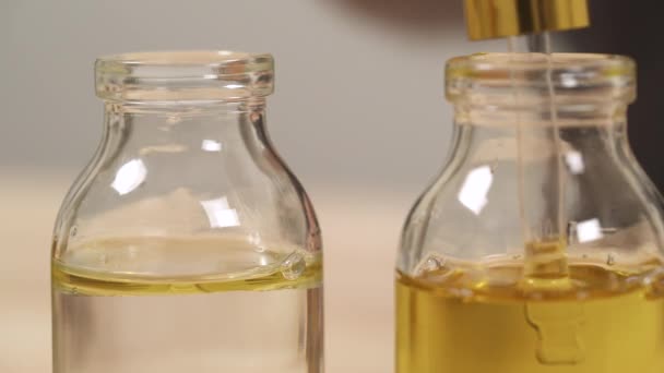 Närbild Pipetten Fylld Med Olja Från Den Första Flaskan Oljedropparna — Stockvideo
