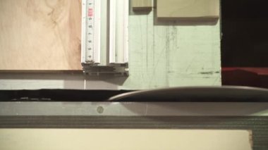 A top view of a table circular saw cutting two small pieces from a plywood board at a right angle