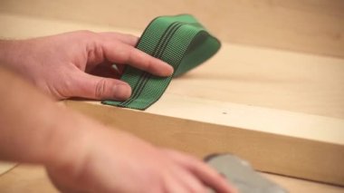 A close-up view of a staple gun attaching webbing to a wooden frame with staplers