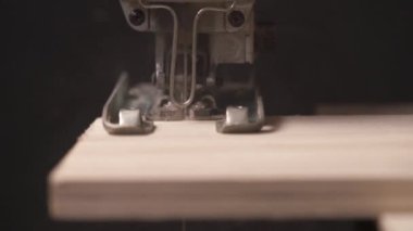 Bir kontrplak parçasını kesen elektrikli bir yapbozun ön görüntüsü.
