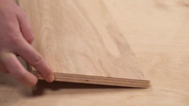 A close-up of man's hand holding a tape measure for measuring pieces of plywood