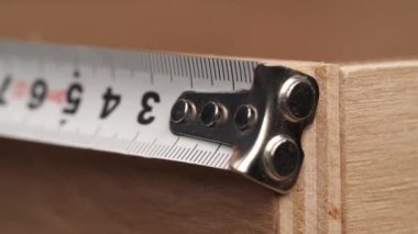 A close-up of plywood measured by a measuring tape