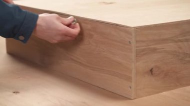 A close-up of man's hand holding a tape measure for measuring the size of wooden box