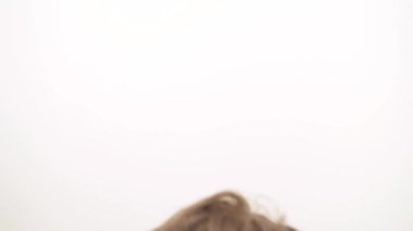 A close-up of beautiful woman taking away her long curly hair from the face, correcting the hair style and sincerely smiling