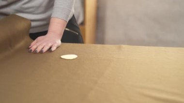 A demonstration video of a tailor measuring the material and preparing it for cutting.