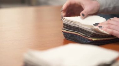 Nude palette tissue samples, choice of fabrics for upholstery. Decorator or tailor touching textile's textures fabric swatches.