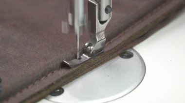 Close-up of a leatherworker stitching leather cloth on sewing machine in action. Textile factory