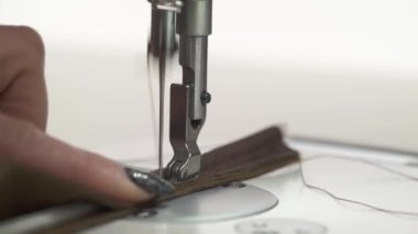 Leatherworker finishes sewing leather parts. Leather cloth stitching on sewing machine in action