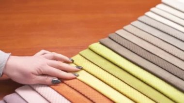 A demonstration video of a woman touching colorful tissue samples and choosing a fabric.