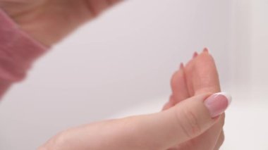 A close-up demonstration of squeezing the eye contour cream on the female finger with beautiful manicure