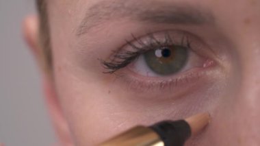 Make professional make-up. The woman applied concealer under the eyes. Conceal dark color around the eyes. Masks the deficiencies