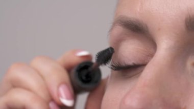 Macro shot of a beautiful young woman using mascara. Make up eyelashes of green eyes